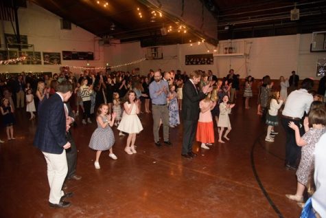 Dads and their daughters clap along and dance to “Cha Cha Slide” by DJ Casper.